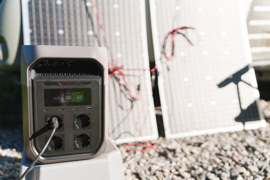 Portable power station with solar panel charging gadgets near a travel trailer caravan