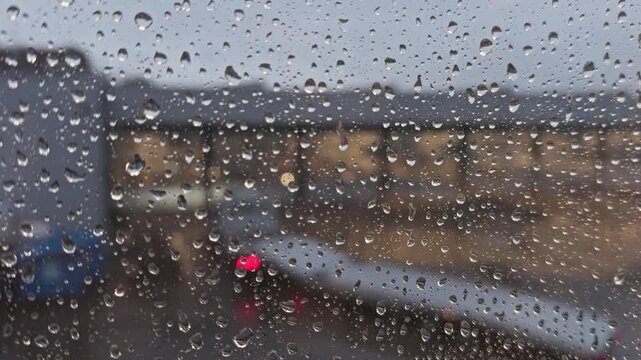 Raindrops on a window, with buildings in the background on a rainy day.
