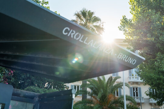 Bari, Italy - June 31, 2026: Crollalanza Bruno street sign on modern canopy structure framed by palm trees and historic building facade in city center