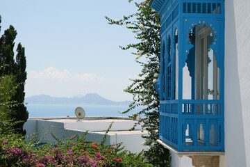 Fototapeta premium White Building with Blue Shutters and Bougainvillea in Mediterranean Town
