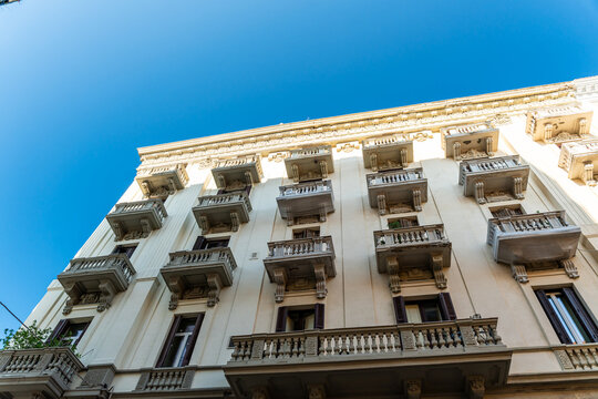 Bari Italy historic apartment building facade with ornate balconies and classical architecture, low angle view against clear blue sky on sunny day