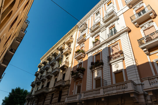 Bari Italy residential apartment buildings with ornate balconies and terracotta facade along narrow urban street, classic southern Italian architecture in warm afternoon light