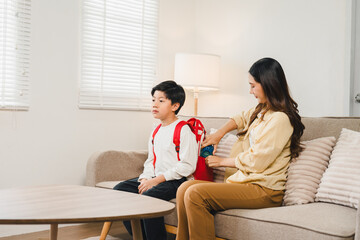 Fototapeta premium Asian mother packing school bag for her son before class at home