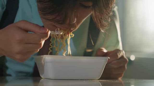 Asian man stirring noodles closeup savoring flavor, hands and disposable fork in frame, steam and texture visible, concentrated bite and expressive relief, warm cinematic glow and intimate detail