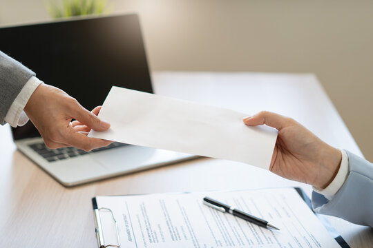 Close up of employee handing resignation letter or application to manager.