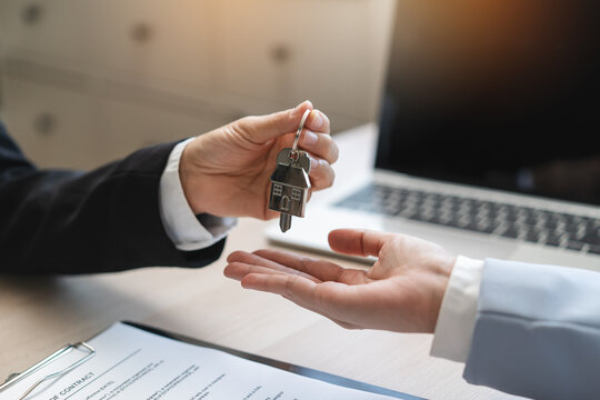 Realtor agent giving a key of apartment to new owner after signed lease agreement
