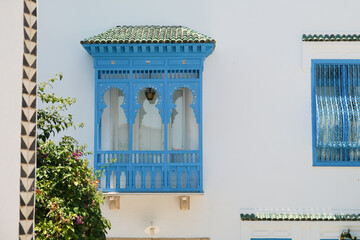 Fototapeta premium White Building with Blue Shutters and Bougainvillea in Mediterranean Town
