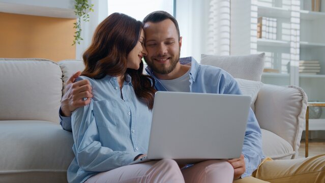 Happy smiling Caucasian talking using laptop for e-commerce shopping joyous deciding agreeing hug successful buying choosing family talk buy with online computer store cuddling hugging at home