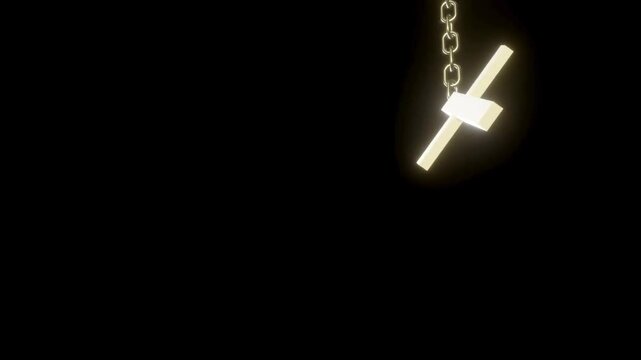 Glowing golden cross necklace pendant swaying gently on silver chain against solid black studio background.