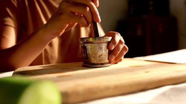 hands of a woman making spices in a mortar in the kitchen