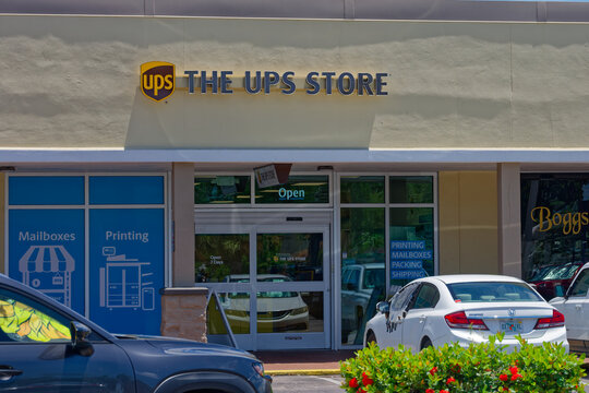 Exterior view of a UPS Store storefront offering mailboxes, printing, packing and shipping services. Editorial Use Only August 8, 2026 St. Petersburg , FL USA. Suburban shopping plaza with parked cars