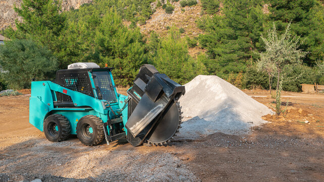 Compact Skid Steer Loader with Wheel Saw Trenching Attachment on a Construction Site