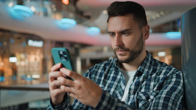 Serious Caucasian business man using mobile phone social media chat scrolling online application male client businessman browsing smartphone cyberspace chatting with cellphone device in shopping mall