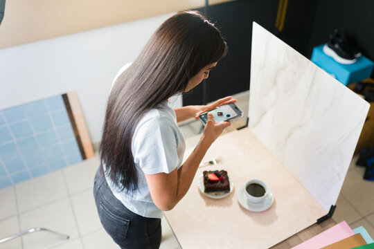 Top view of a woman creating food content for social media, taking product pictures with smartphone in studio