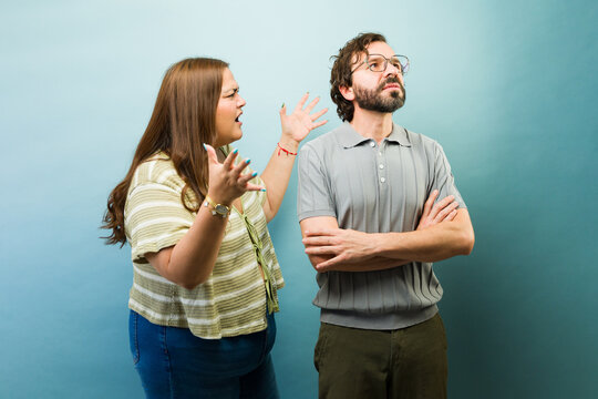 Plus size woman shouting and arguing with an indifferent man turning away during a relationship conflict