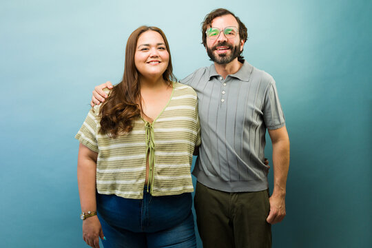 Cute couple smiling at camera, celebrating love and body positivity on a blue background