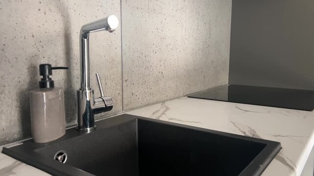 A modern kitchen interior features a dark sink, stone countertop, and stainless steel appliances for a sleek contemporary look. Kitchen renovation portfolios, interior design magazines