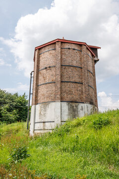 Historic Round Brick Silo Tower on a Grassy Hill Under Cloudy Skies