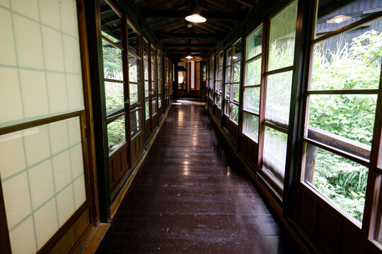 Traditional Japanese Wooden Corridor with Glass Windows Overlooking Lush Greenery