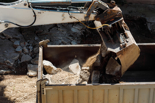 Heavy machinery clears debris from a site into a dumpster