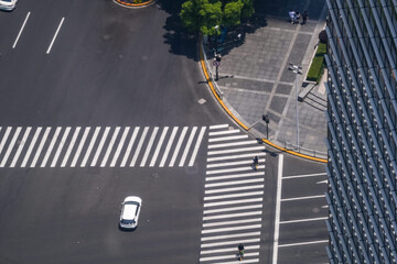 Elevated view of a commercial district corner shared by buses, cars and people on foot, trees and planters screening the office entrance from the roadway, high above the daily commute. © ultramansk