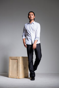Asian sexy man wearing a white shirt and suit pants against a gray background