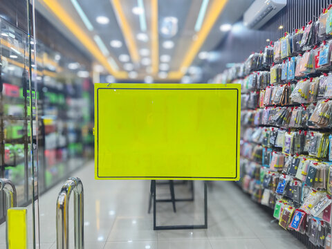 ​Blank yellow sign mockup in retail mobile phone accessory store interior with copy space for text promotion discount advertisement