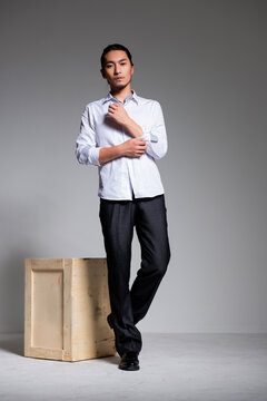 Asian sexy man wearing a white shirt and suit pants against a gray background