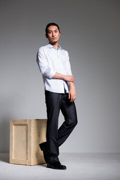 Asian sexy man wearing a white shirt and suit pants against a gray background