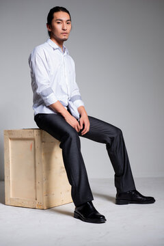 Asian sexy man wearing a white shirt and suit pants against a gray background