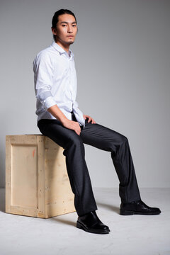 Asian sexy man wearing a white shirt and suit pants against a gray background