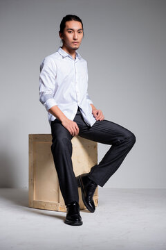 Asian sexy man wearing a white shirt and suit pants against a gray background