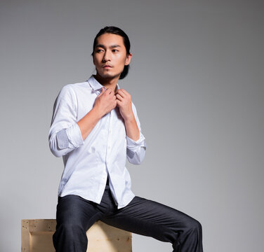 Asian sexy man wearing a white shirt and suit pants against a gray background