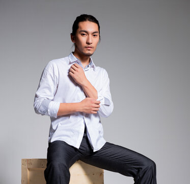 Asian sexy man wearing a white shirt and suit pants against a gray background