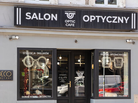 Poznan, Poland - February 28, 2026: Olaf Tabaczynski Optic Cafe storefront exterior displaying neon glasses signage for vision care, optometry, and professional eyewear styling services