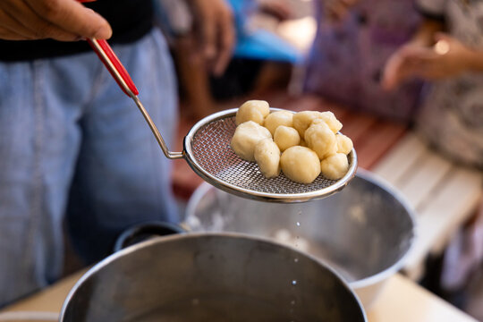 Process of making food at a gathering with people near a large pot