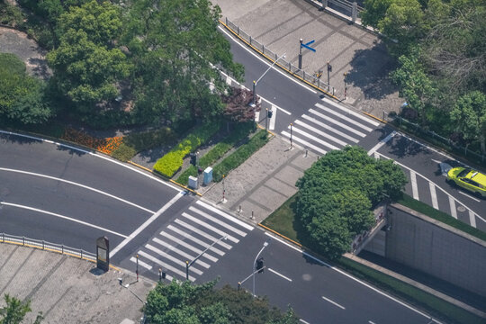 Aerial view of pedestrian crossings beside a landscaped road underpass ramp, flowering beds edging the descent into the underpass, a study in street geometry and lane use.
