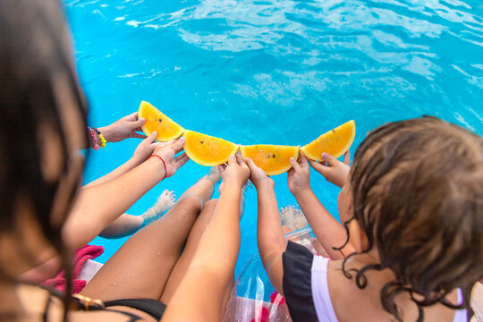 Children eating watermelon by the pool. Selective focus.