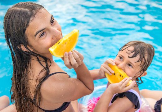Children eating watermelon by the pool. Selective focus.