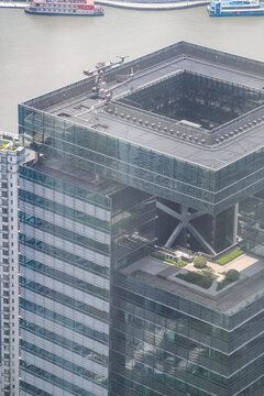 High angle view of the crown of an office high rise with a sky garden terrace, a giant steel cross brace exposed across the upper elevation, how a business quarter organises space.