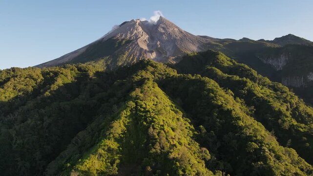 Scenic Aerial Footage of Merapi Volcano with Lush Tropical Forested Slopes During Morning Under a Clear Sky, Vibrant and Wonderful Mountain Scenery of Volcanic Landscape in Yogyakarta, Indonesia.