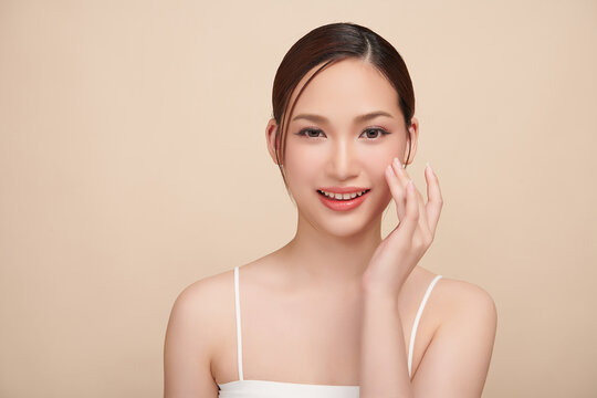A beautiful young Asian woman with clean, fresh skin against a beige background. Skincare, facial treatment, cosmetology, beauty, and spa. An elegant portrait of an Asian woman.