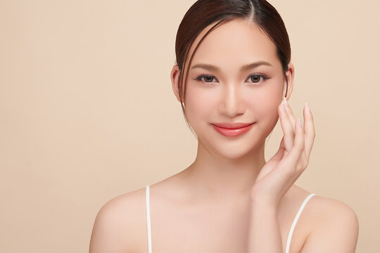 A beautiful young Asian woman with clean, fresh skin against a beige background. Skincare, facial treatment, cosmetology, beauty, and spa. An elegant portrait of an Asian woman.