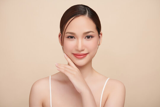 A beautiful young Asian woman with clean, fresh skin against a beige background. Skincare, facial treatment, cosmetology, beauty, and spa. An elegant portrait of an Asian woman.