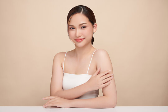 A beautiful young Asian woman with clean, fresh skin against a beige background. Skincare, facial treatment, cosmetology, beauty, and spa. An elegant portrait of an Asian woman.