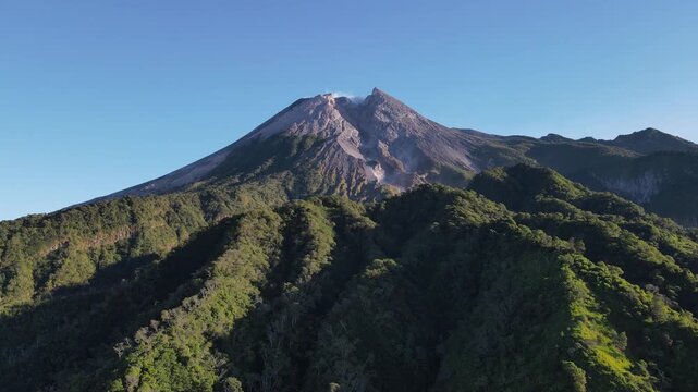 Scenic Aerial Footage of Merapi Volcano with Lush Tropical Forested Slopes During Morning Under a Clear Sky, Vibrant and Wonderful Mountain Scenery of Volcanic Landscape in Yogyakarta, Indonesia.