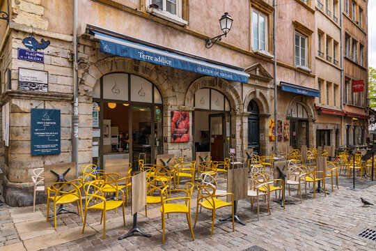 Lyon, France - July 27, 2026: Empty outdoor ice cream shop terrace with bright yellow chairs at Place de la Baleine in historic Vieux Lyon.