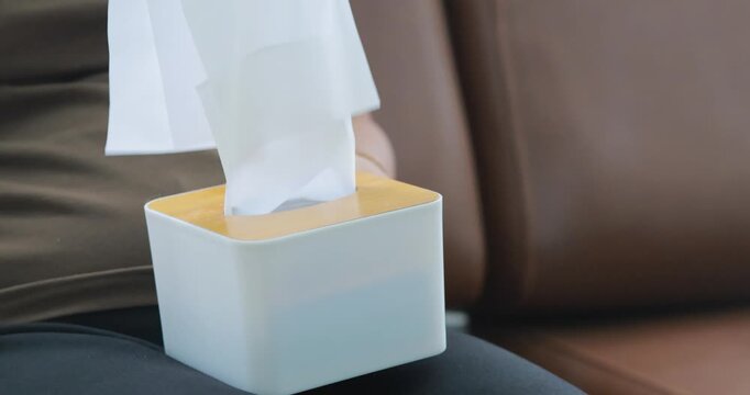 Hand pulling a tissue from a tissue box, tissue box, hygiene and cleanliness, healthcare, daily living, home essentials, and personal care, close-up