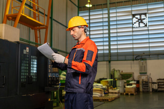 Engineer, factory, worker, helmet, safety, uniform, machine operator checks document near industrial equipment in workshop