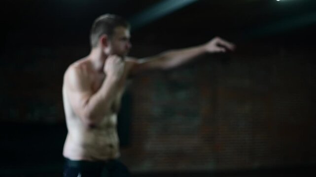 Dark lit gym 120 frames per second video, man in shape shadow boxing, soft focus b roll video, background bokeh, boxing mma workout